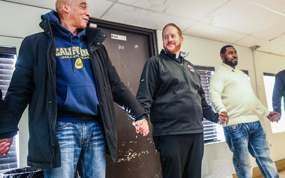 Fr. Matt O'Donnell, pastor of St. Columbanus Parish in Chicago, prays with volunteers before they open the church's Wednesday food pantry in a file photo. In 2020, the church received an estimated $70,000 in Paycheck Protection Program loans. (CNS)