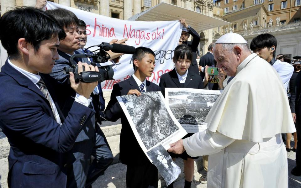 Pope Francis examines photos of the aftermath of the 1945 atomic bombing of Japan as he greets members of the Hiroshima and Nagasaki Youth Peace Messengers at his weekly general audience June 19. (CNS/Vatican Media)