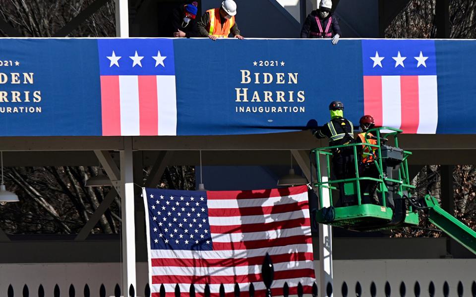 Workers in Washington place Biden-Harris inauguration banners on the inaugural parade viewing stand across from the White House Jan. 14. (CNS/Erin Scott, Reuters)