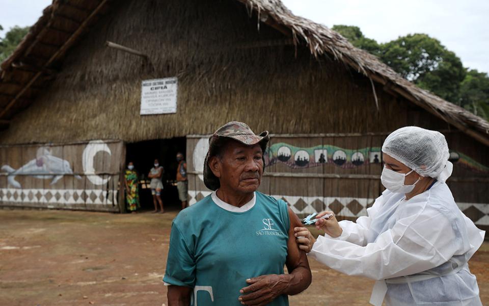 An Indigenous man receives the AstraZeneca/Oxford COVID-19 vaccine from a municipal health worker in the Sustainable Development Reserve of Tupe in Manaus, Brazil, Feb. 9. (CNS/Reuters/Bruno Kelly)