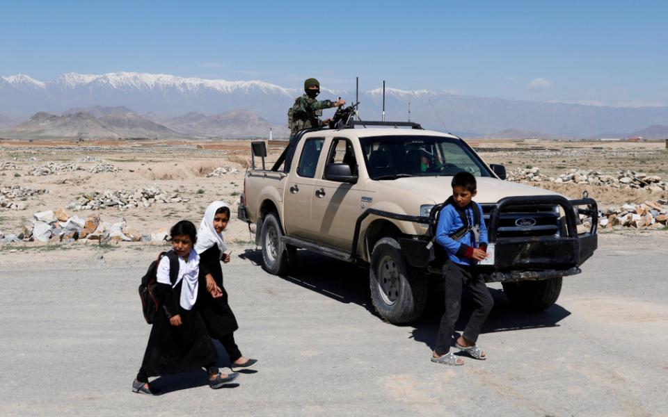 Schoolchildren walk past an Afghan National Army soldier keeping watch at a checkpoint on the outskirts of Kabul, Afghanistan, April 21, 2021. (CNS/Reuters/Mohammad Ismail)