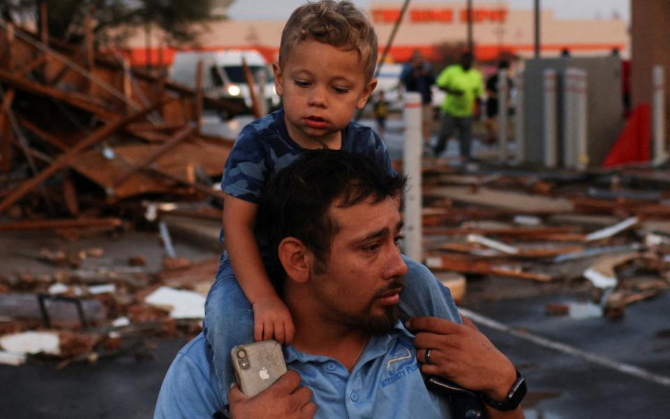 Arturo Ortega and his son, Kaysen Ortega, 2, survey the damage to a shopping center after a tornado touched down in Round Rock, Texas, March 21, 2022. (CNS/Reuters/Tamir Kalifa)