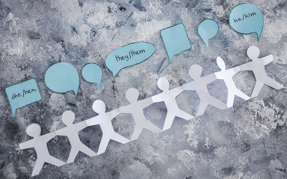 Paper cutout figures with speech bubbles saying their pronouns (Dreamstime/Faithiecannoise)