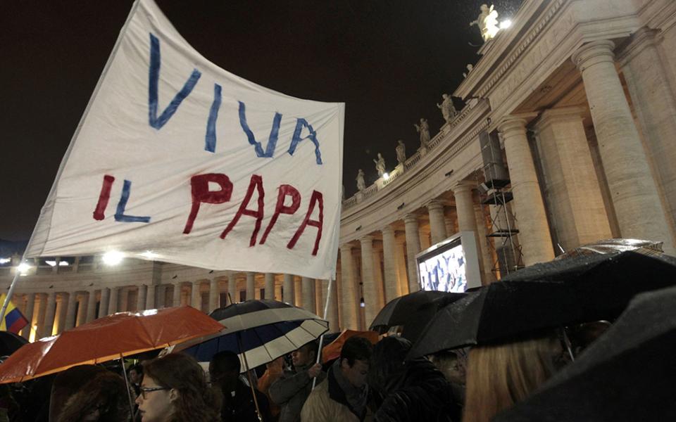 Pilgrims wave a banner saying "Viva il papa" ("Long live the pope") as white smoke rises from the chimney above the Sistine Chapel, indicating a new pope has been elected at the Vatican, in this photo from March 13, 2013. The conclave to elect a new pope met over two days before making a decision. (CNS/Reuters/Giampiero Sposito)