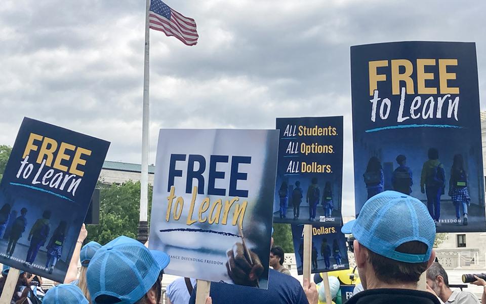 People gathered in front of the U.S. Supreme Court April 30 hold signs supporting that a Catholic charter school, St. Isidore of Seville Catholic Virtual School in Oklahoma, should get state taxpayer support. (NCR photo/Carol Zimmermann)