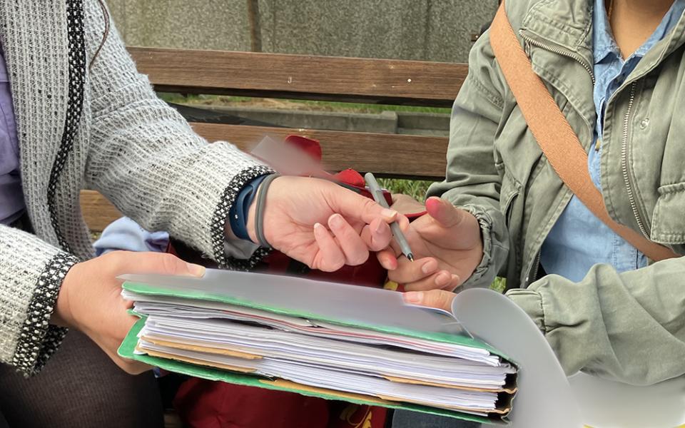 A client and her attorney, at left, go over paperwork at the George H. Fallon Federal Building in Baltimore, a check-in field office for the U.S. Immigrations and Customs Enforcement. Documents have been obscured for privacy. (NCR photo/Patricia Zapor)
