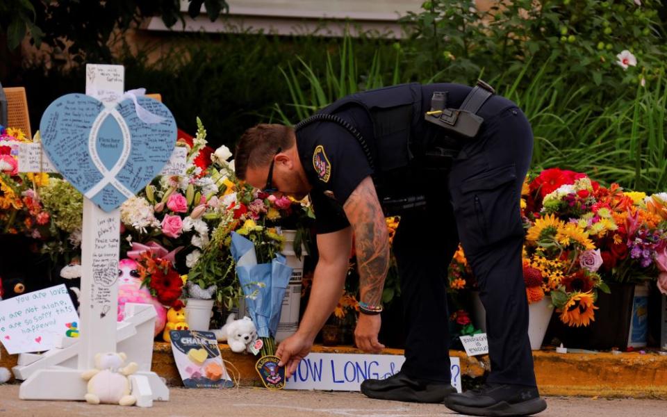  A police officer places a patch at a makeshift memorial at Annunciation Catholic Church after the Aug. 27 fatal shooting at the school Aug. 29 in Minneapolis. (AP/Bruce Kluckhohn)
