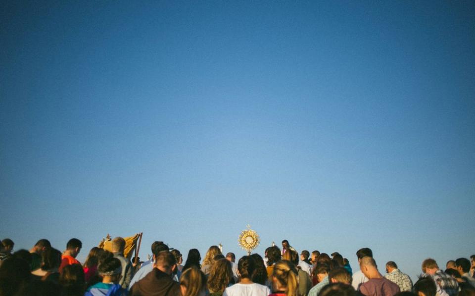 A group of people, including one person carrying a monstrance.