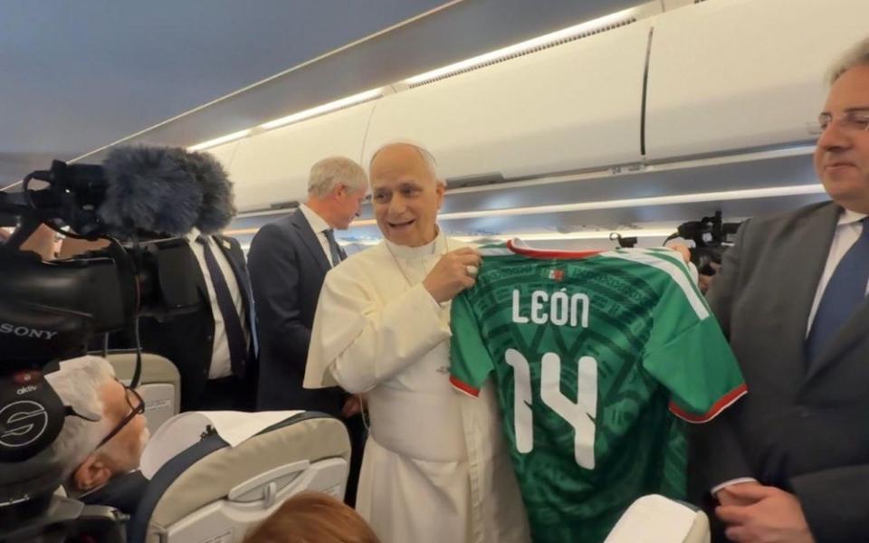 Pope Leo XIV holds a personalized Mexican soccer jersey given to him by Vatican journalist Valentina Alazraki, from Mexico, June 6, on the flight from Rome to Madrid at the start of his visit to Spain. Leo said he hoped the World Cup, which starts June 11, would be a source of unity. (Vatican press pool)