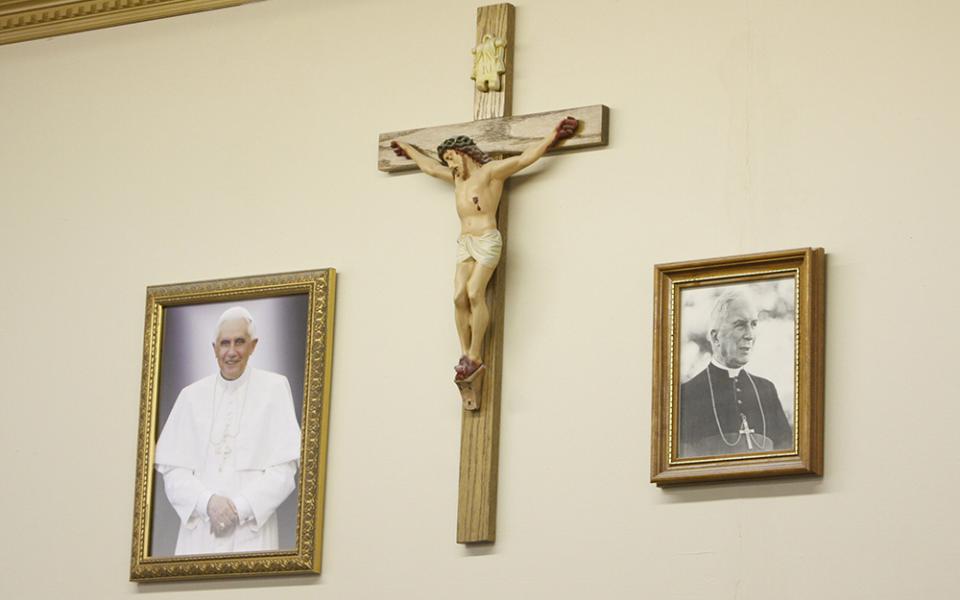 Portraits of Pope Benedict XVI and Archbishop Marcel Lefebvre, founder of the Society of St. Pius X, flank a crucifix in the community room at St. Michael the Archangel Chapel in Farmingville, New York, Feb. 1, 2009. (CNS/Gregory A. Shemitz)