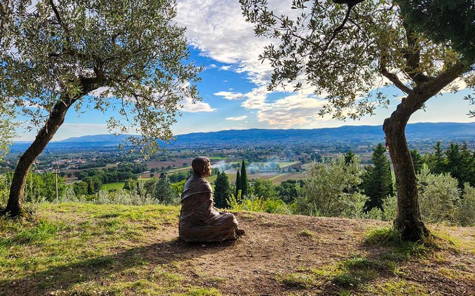 A bronze sculpture of St. Francis of Assisi looks out over the medieval Italian town outside the Church of San Damiano on Oct. 4, 2025. (NCR photo/Brian Roewe)