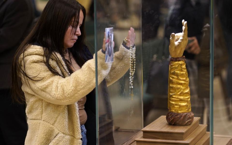 A woman prays in front of a glass-encased reliquary containing a bone from the arm of St. Jude the Apostle at St. Jude Church in Mastic Beach, N.Y., Nov. 27, 2023. (OSV News/Gregory A. Shemitz)