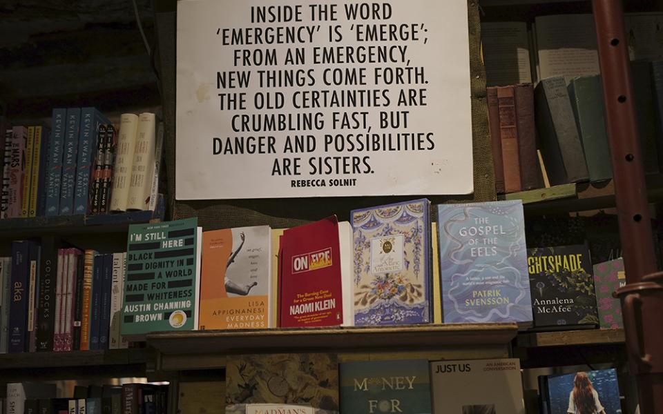A panel on "Emergency" by Rebecca Solnit hangs on the book shelves of the English and American literature Shakespeare and Co. bookstore, in Paris, France, Nov. 05, 2020. (AP photo/Francois Mori)
