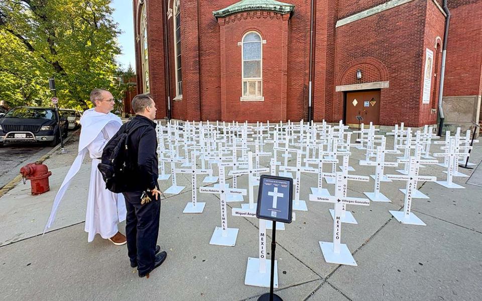 Dominican Fr. Brendan Curran, of Priests for Justice for Immigrants, and Fr. Thomas Boharic, pastor of Mother of the Americas Parish, stand by the traveling installation of immigrant crosses outside the church in Chicago's Little Village neighborhood, Oct. 3, 2026. (NCR photo/Camillo Barone)