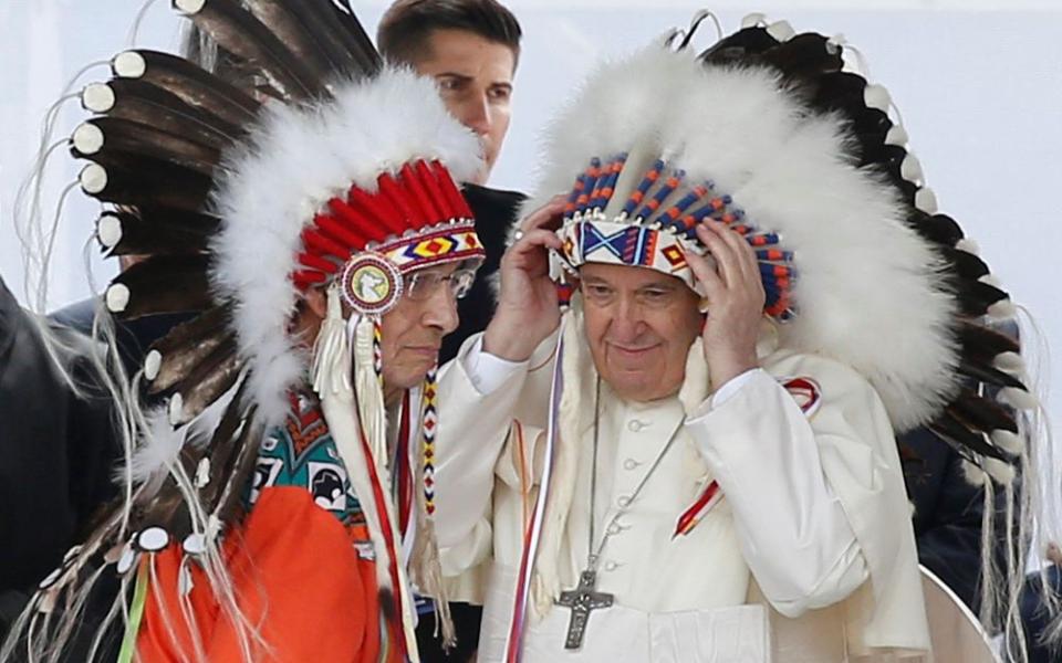 Pope Francis adjusts a traditional Indigenous headdress during a meeting with First Nations, Métis and Inuit communities at Maskwacis, Alberta, July 25. During a weeklong visit to Canada, the pope met with Indigenous groups.