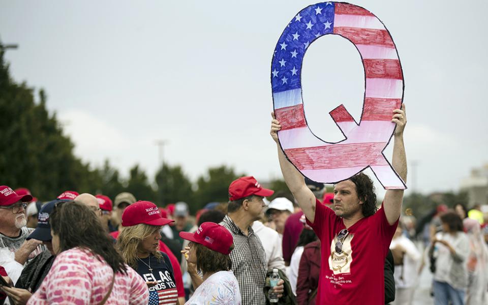 In this Aug. 2, 2018, file photo, a protester holds a Q sign, referencing the fringe conspiracy theory QAnon, as he waits in line with others to enter a campaign rally with then-President Donald Trump in Wilkes-Barre, Pennsylvania. (AP/Matt Rourke, File)