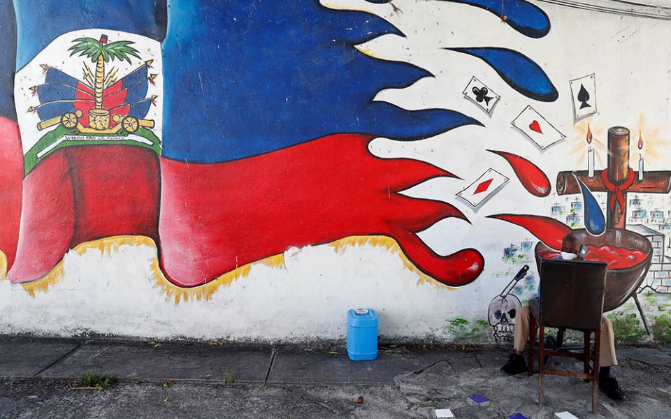 A man speaks on a phone next to a mural in the Little Haiti neighborhood of Miami July 8. (Newscom/Reuters/Shannon Stapleton)