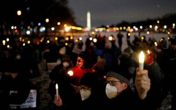 People hold up candles during a candlelight vigil on the National Mall in Washington, D.C., Jan. 6. It was the first anniversary of the attack on the Capitol by supporters of former President Donald Trump. (CNS/Reuters/Tom Brenner)
