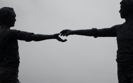 A silhouette of the statue Hands Across the Divide is pictured in Londonderry, Northern Ireland. The bronze was unveiled in 1992, 20 years after Bloody Sunday, when British troops killed 14 Catholic demonstrators. (CNS/Reuters/Clodagh Kilcoyne)