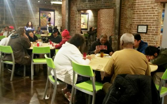 People enjoy dinner at Bishop Sullivan Center's One City Café, a restaurant-style community kitchen offering free meals in Kansas City, Missouri, as volunteers and staff serve them Feb. 26. (NCR photo/Maria Benevento)