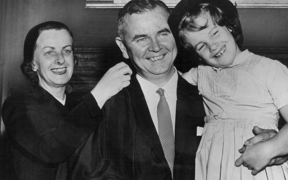 Justice William J. Brennan Jr. holds his daughter, Nancy, as his wife, Marjorie helps him with his robe at the Supreme Court building in this 1956 file photo. Brennan died July 24, 1997, at age 91. (CNS file photo)