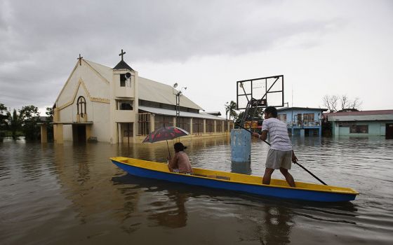 People make their way by boat past a church along a flooded road in Bulacan, Philippines, Aug. 21, 2013, following heavy monsoon rains. (CNS/Reuters/Erik de Castro)