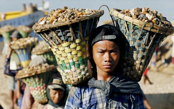 Children in Yangon, Myanmar, carry baskets loaded with gravel used for construction in 2015. (CNS/EPA/Rungroj Yongrit)