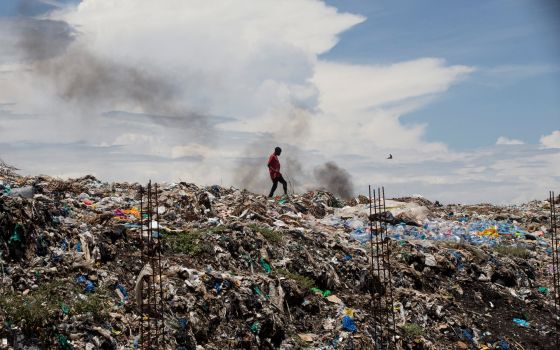 A man walks in a garbage dump in Kisumu, Kenya, April 18. (CNS/Baz Ratner, Reuters)