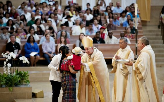 Archbishop José Gomez blesses a Mayan family from Guatemala during the presentation of the gifts at a June 18 Mass celebrated in recognition of all immigrants at the Cathedral of Our Lady of the Angels in Los Angeles.