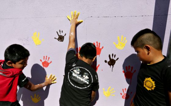 Children paint a wall with their handprints in early January 2017 as part of a project to recover walls painted with gang graffiti in Villa Nueva, Guatemala. (CNS/EPA/Esteban Biba)