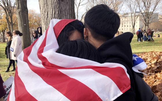 Young adults protect themselves from the cold by wrapping themselves in a U.S. flag near the U.S. Capitol during a rally Dec. 6, 2017, in support of undocumented immigrants. (CNS/Rhina Guidos)