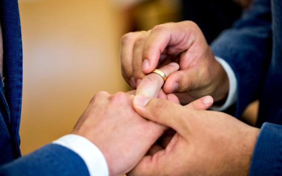 Two same-sex partners exchange wedding bands during a 2017 ceremony at the civil registry office in Munich. (CNS/EPA/Marc Mueller)