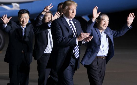 President Donald Trump walks with three U.S. detainees arriving May 10 at Joint Base Andrews, Maryland, after they were released by North Korea as a goodwill gesture. (CNS/EPA/Michael Reynolds)