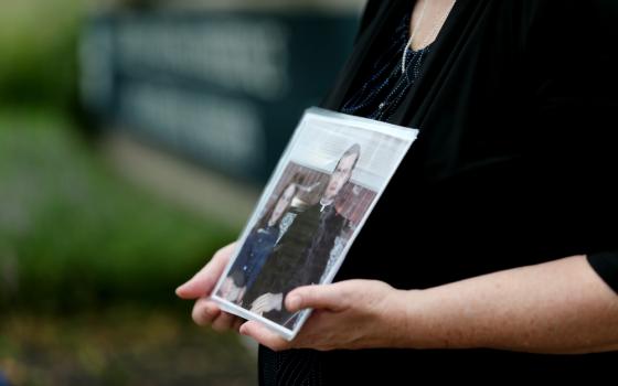 Becky Ianni holds a photo of herself as a child with a priest Aug. 21 outside the headquarters of U.S. Conference of Catholic Bishops in Washington. Ianni says she was abused by the priest in the photo. (CNS/Bob Roller)