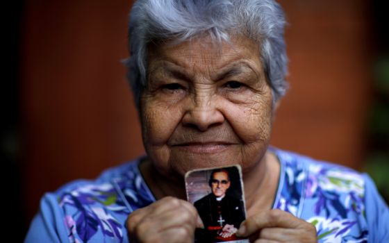 Human rights activist Guadalupe Mejia poses for a picture with a stamp showing Blessed Óscar Romero Oct. 12 at her home in San Salvador, El Salvador. (CNS/Reuters/Jose Cabezas)
