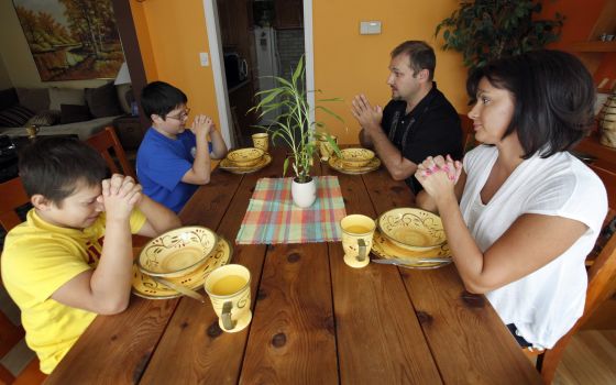 A family prays together before a meal in 2012 at their Chicago home. (CNS photo/Karen Callaway, Catholic New World)