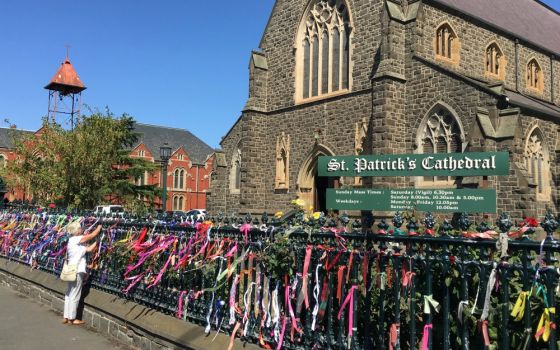 A woman puts a ribbon on the fence of St. Patrick's Cathedral in Ballarat, Australia, in February 2019. The ribbons raise awareness and show support for victims of abuse. (CNS/Reuters/Jonathan Barrett)