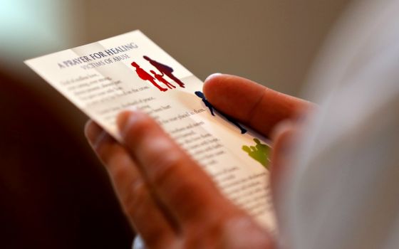 A clergyman reads a prayer card during a Mass with special intentions for survivors of abuse and for abuse prevention in the chapel of the headquarters of the U.S. Conference of Catholic Bishops in Washington April 8. (CNS/Bob Roller)