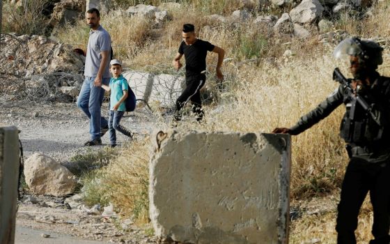 An Israeli border policeman stands guard not far from Ramallah, West Bank, May 17, 2019, as Palestinians make their way to attend Friday prayer at al-Aqsa mosque in Jerusalem's Old City. (CNS/Reuters/Raneen Sawafts)