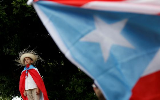 A youth draped in a Puerto Rican flag attends a rally to celebrate the resignation of Puerto Rican Gov. Ricardo Rosselló in San Juan July 25. (CNS/Reuters/Marco Bello)