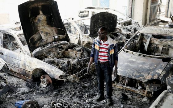 Nigerian entrepreneur Basil Onibo, one of the victims of a recent spate of xenophobic attacks in South Africa, looks at the burned cars at his dealership in Johannesburg Sept. 5. (CNS/Reuters/Siphiwe Sibeko)