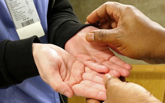 A personal care assistant has her hands anointed in a 2018 photo. (CNS/Gregory A. Shemitz)