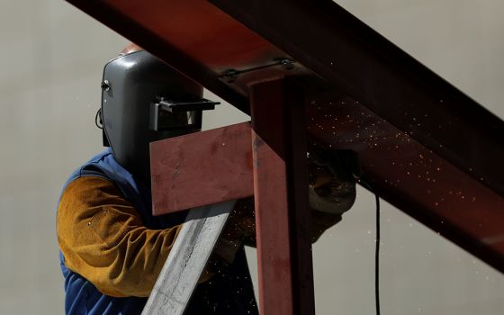 A construction worker uses a grinder on a metal beam at a construction site Aug. 10, 2017, in Los Angeles. (CNS/Reuters/Mike Blake)