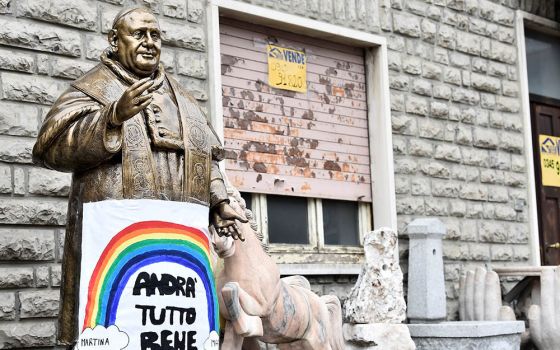 A sign reading "All will be well" hangs on a statue of St. Pope John XXIII in Zogno, Italy, near Bergamo, March 22, 2020. (CNS/Reuters/Flavio Lo Scalzo)