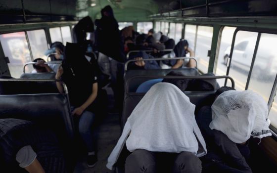 Guatemalan migrants cover themselves while on a bus outside La Aurora International Airport in Guatemala City March 19 after being deported from the U.S. (CNS/Reuters/Fabricio Alonso)