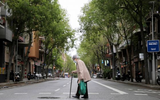 An elderly woman wears a protective face mask as she walks with shopping bags during the COVID-19 pandemic in Barcelona, Spain, April 1, 2020. (CNS photo/Nacho Doce, Reuters)