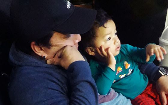 Juan Vasquez, a grocery store worker in Uniondale, New York, cuddles with his toddler Robert while watching TV at home March 28, 2020. (CNS/Courtesy of Tanya Granillo de Vasquez)