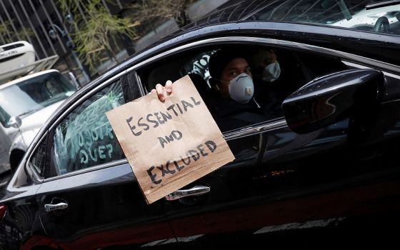 A worker in New York City holds a sign from a car during a caravan demonstration for the rights of essential immigrant workers April 21, 2020. (CNS/Reuters/Mike Segar)