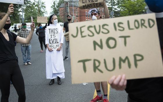 A woman religious and protesters in Washington gather near the Capuchin College June 2 as President Donald Trump and first lady Melania Trump visited the nearby St. John Paul II National Shrine. (CNS/Tyler Orsburn)