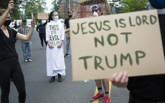 A woman religious and protesters in Washington gather near the Capuchin College June 2 as President Donald Trump and first lady Melania Trump visited the nearby St. John Paul II National Shrine. (CNS/Tyler Orsburn)